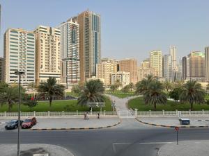 a city with tall buildings and palm trees and a street at Park view bedroom in family apartment in Sharjah