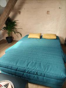 Una cama azul con dos almohadas encima. en Cocoon Boisé, en Les Portes du Coglais