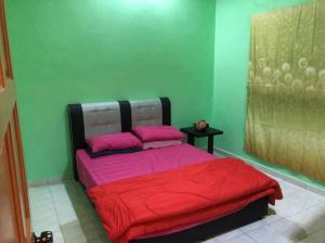 a bedroom with a bed with red sheets and pink pillows at KJ Homestay Balok Kuantan in Kampong Chengal Lempong