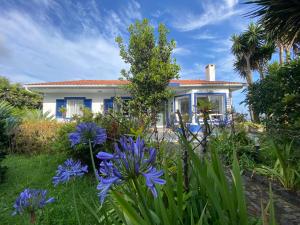 Quinta dos Bravos في Pico da Pedra: أمامه منزل به زهور زرقاء