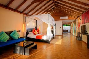 a bedroom with a bed and a couch in a room at Canareef Resort Maldives in Meedhoo