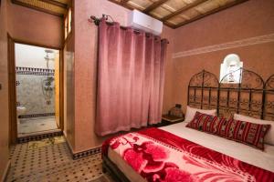 een slaapkamer met een bed met een rode sprei bij DAR NOUR in Tafraoute