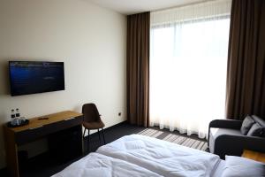a hotel room with a bed and a desk and a window at Готель Карпатія in Mukacheve