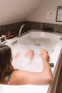 Holiday Home Relax في إبير: امرأة جالسة في حوض الاستحمام عقد الشراب