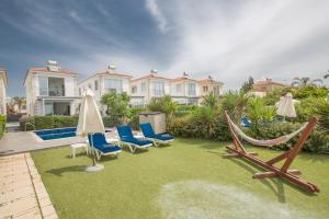 een tuin met stoelen en hangmatten en een huis bij Villa Suri, Luxury Seafront Villa in Ayia Napa
