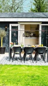 un patio con mesa y sillas en un patio trasero en Stayatsas Tiny House Julia in de bossen op de Veluwe! en Epe