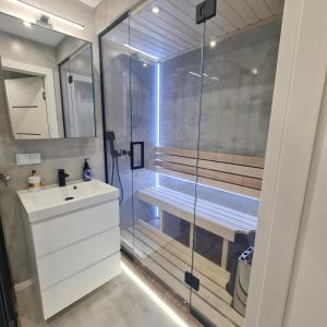 een badkamer met een douche en een witte wastafel bij Green De Lux Apartament Dziwnów in Dziwnów