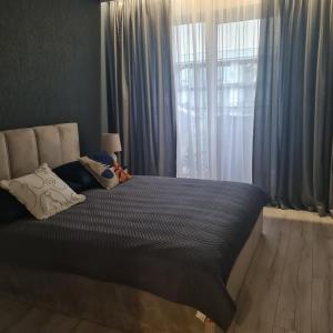 een slaapkamer met een bed met blauwe gordijnen en een raam bij Green De Lux Apartament Dziwnów in Dziwnów