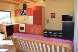 une cuisine avec des placards rouges et un banc dans l'établissement Martlerhof Urlaub auf dem Bauernhof, à Campo di Trens