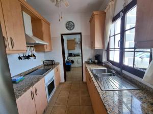 a kitchen with wooden cabinets and a sink and a window at Villa Lagarto heated pool aircon central Playa Blanca in Playa Blanca