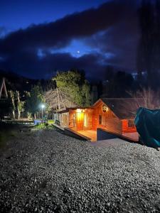 a house on a gravel road at night at Cuatro Cerros Hostel in San Carlos de Bariloche