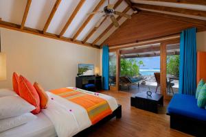 a bedroom with a bed and a view of the ocean at Canareef Resort Maldives in Meedhoo