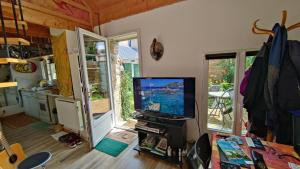 a living room with a flat screen tv and a kitchen at Maisonnette avec cour in Ploubezre