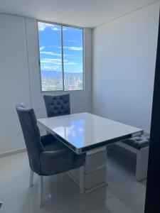 uma mesa branca e cadeiras num quarto com uma janela em Encanto urbano con la mejor vista y ubicación ! em Cúcuta