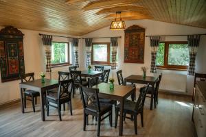 a dining room with tables and chairs and windows at Magda Garden in Cârțișoara