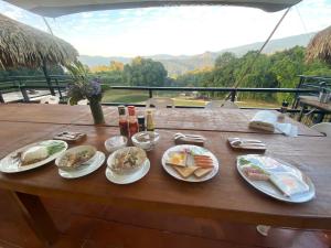 a wooden table with plates of food on it at Daelorpu 2 แดลอปู in Ban Yang