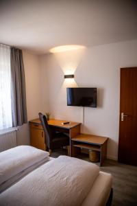 ein Hotelzimmer mit einem Schlafzimmer mit einem Schreibtisch und einem Bett in der Unterkunft Hotel Schmidt garni in Essen