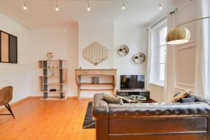 a living room with a leather couch and a fireplace at Le Discret de la Craffe - A 5 min de la Place Stanislas in Nancy
