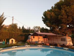 a campsite with a camper and a trailer and a swimming pool at Caravana- Glamping Casa tortuga in La Nucía