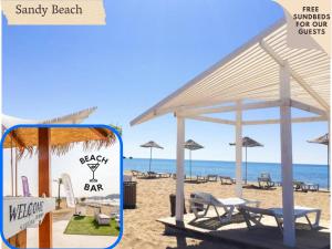 einen Strand mit Liegestühlen und Sonnenschirmen auf dem Sand in der Unterkunft Caesar Resort & SPA in Trikomo