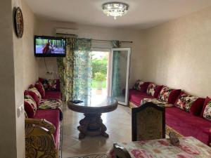 uma sala de estar com um sofá, uma mesa e uma televisão em Ap6 em Saïdia
