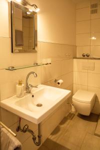 a white bathroom with a sink and a toilet at Hotel Schmidt garni in Essen