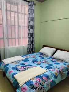 KAJIADOHOMES في Kajiado: غرفة نوم مع سرير مع لحاف من الزهور ونافذة