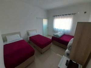 a bedroom with two beds and a window at Pousada Gabriel in São Miguel Arcanjo