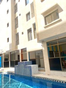 een gebouw met een zwembad voor een gebouw bij Hôtel Ami Bamba in Mbour