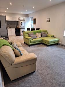 a living room with two green couches and a kitchen at Spacious, modern first floor flat near beach and ferry in East Cowes