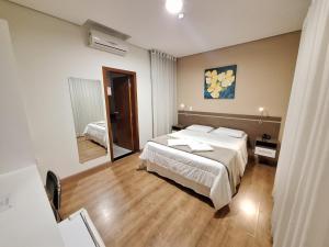 a bedroom with two beds and a large mirror at Hotel Itapema in Valinhos