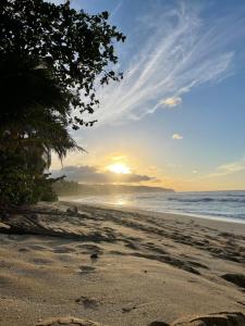 a beach with the sun setting on the horizon at Guest House - V-land in Haleiwa