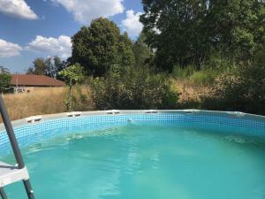 een groot blauw zwembad met een stoel in de tuin bij Chambres d'Hôtes La Fougeraie in Malvières