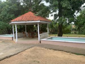 a gazebo with a table and a swimming pool at Blissful Lodgings in Jos
