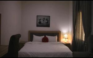 a bedroom with a bed with a red pillow on it at Blissful Lodgings in Jos