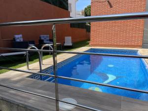 een zwembad gezien door een metalen hek bij Villa for 2 families in Blanes