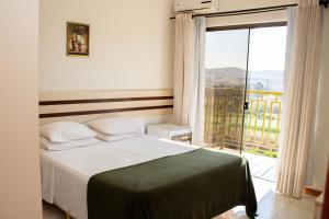 1 dormitorio con cama y ventana grande en Hotel Fazenda Poços de Caldas, en Poços de Caldas