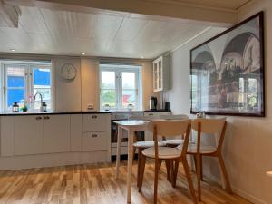 a kitchen with white cabinets and a table and chairs at Cory & Torfinn House in Sørvágur