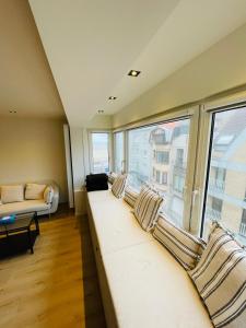 a room with a long couch and a large window at Hip en lichtrijk appartement vlakbij het strand in Knokke-Heist