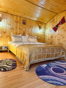 1 dormitorio con 1 cama con paredes de madera y suelo de madera en Cabana doi mesteceni, en Drumu Carului