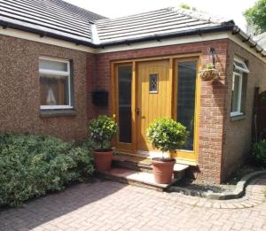 a house with a yellow door and two potted plants at Abbeyside Cottage in Kelso