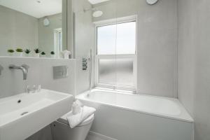 Baño blanco con bañera y lavamanos en Skyline Serviced Apartments - Julians Road en Stevenage