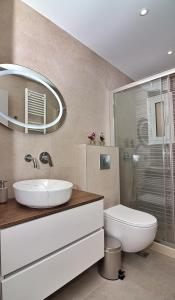 a bathroom with a sink and a toilet and a mirror at Garitsa Gem Suite in Corfu Town