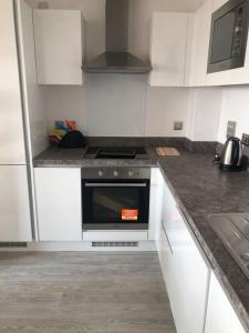 a kitchen with white cabinets and a stove top oven at 3 bedroom apartment free parking in Manchester