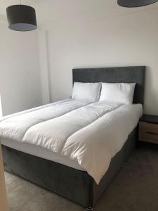 Una cama con sábanas blancas y almohadas. en 3 bedroom apartment free parking, en Mánchester