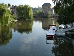 dois barcos estão ancorados num rio perto de um edifício em Maison rénovée Atoué loc em Fresnay-sur-Sarthe