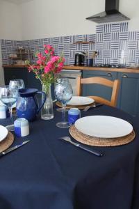 una mesa azul con platos, vasos y flores. en Maison rénovée Atoué loc en Fresnay-sur-Sarthe