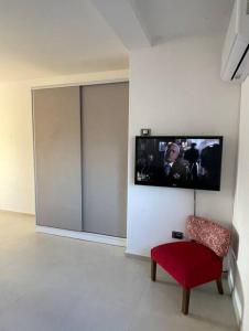 a room with a red chair and a tv on a wall at Departamento a estrenar en los caminos del vino in Maipú