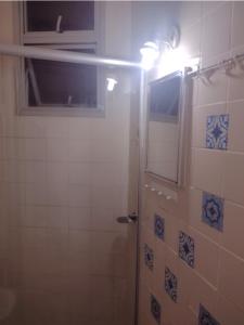 ein Bad mit einer Dusche, einem Fenster und einer Lampe in der Unterkunft Loft encantador centro Guarapari in Guarapari