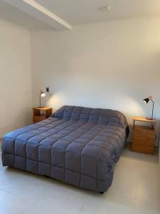 a large blue bed in a room with two tables at Departamento a estrenar en los caminos del vino in Maipú +6 photos